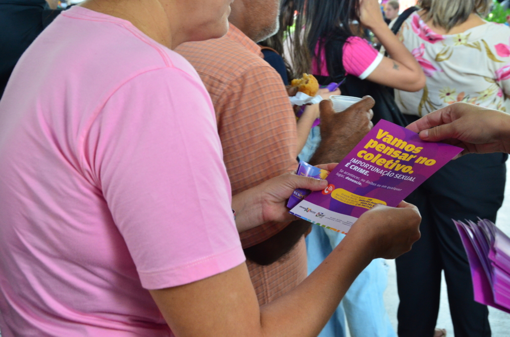 Mulher segurando panfleto contra assédio sexual nos coletivos