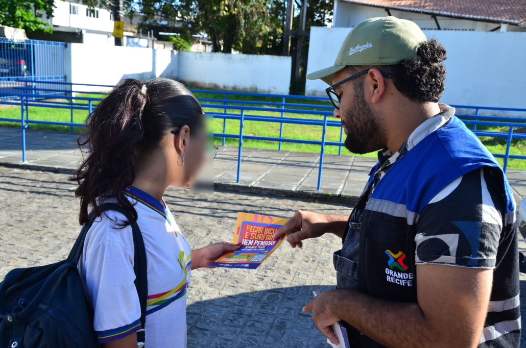 Homem entregando panfleto para uma menina