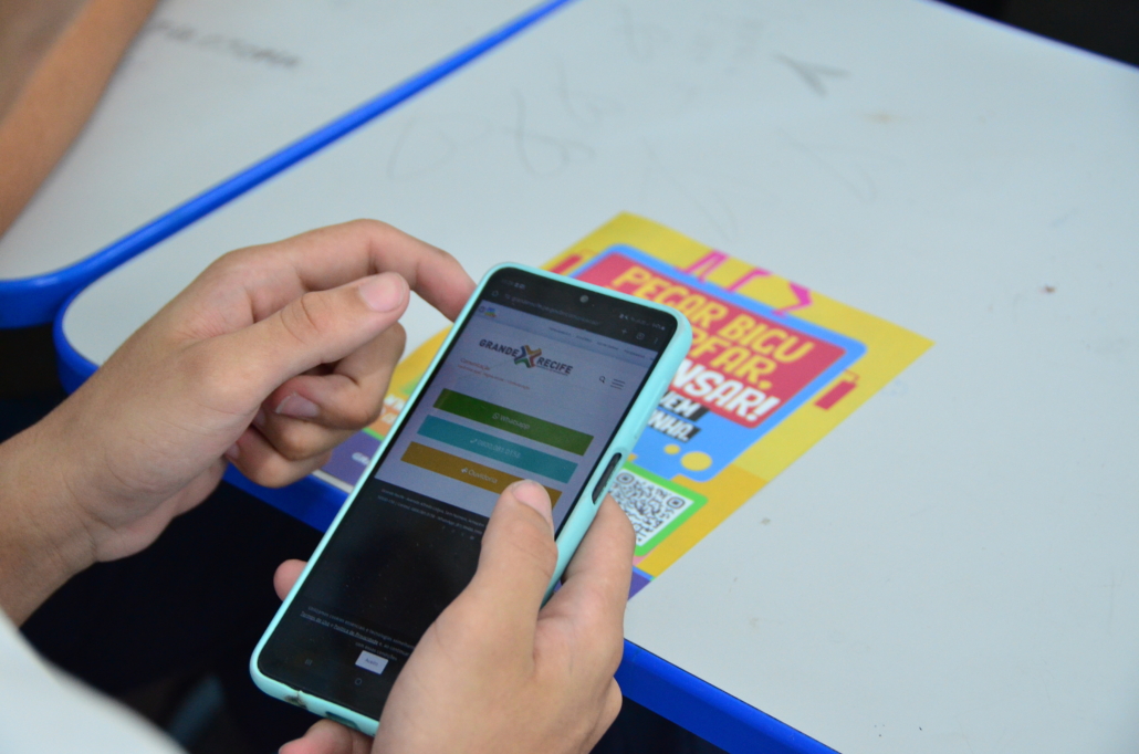 Celular apontando câmera para panfleto que está em segundo plano