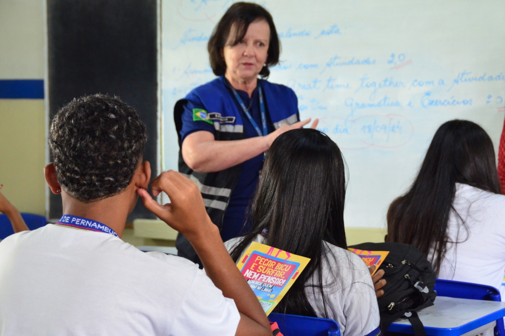 Mulher realizando palestras para alunos e alunas de escolas estaduais