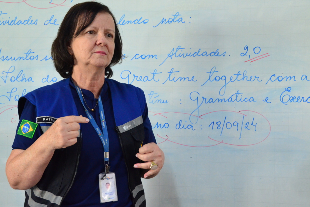 Mulher com colete azul e preto, pela clara e cabelos escuros. 