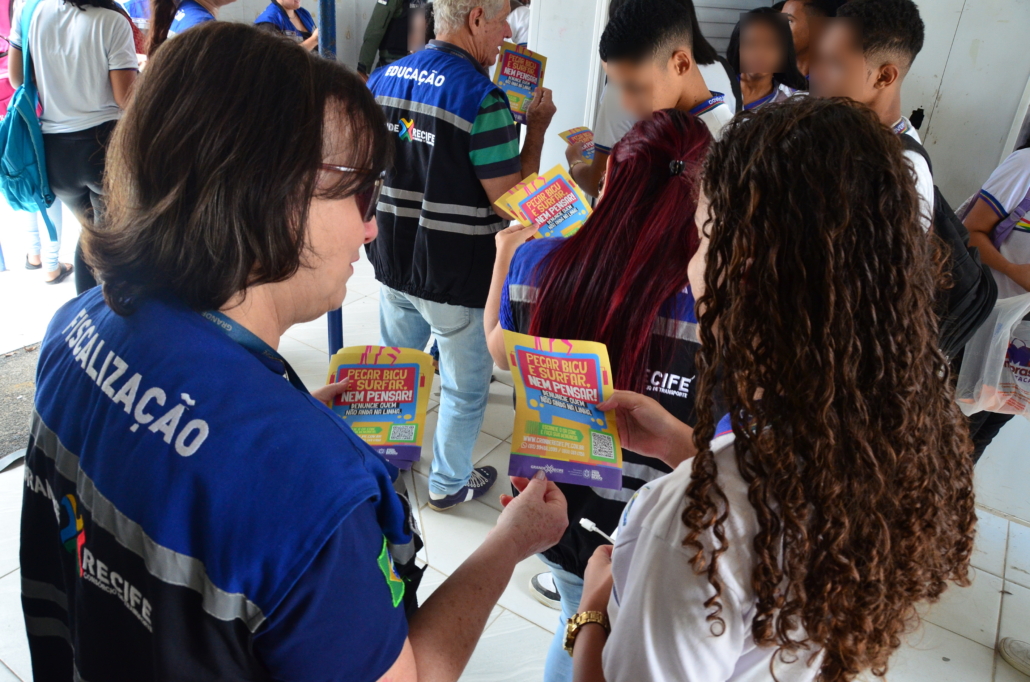 Mulher entregando panfleto para estudante de escola estadual