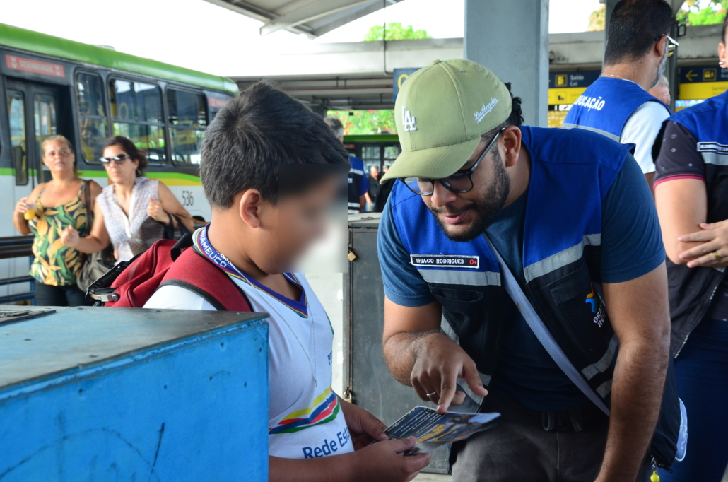 Homem conversando e entregando panfleto para criança que estava esperando ônibus